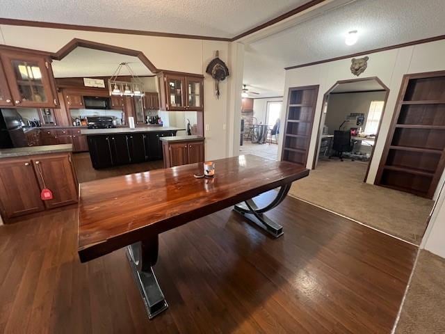 carpeted dining space with a textured ceiling, crown molding, and vaulted ceiling