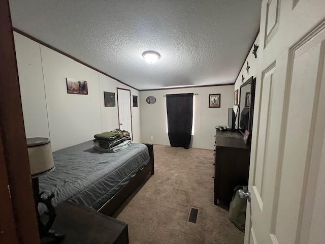 bedroom featuring light carpet, a textured ceiling, and crown molding