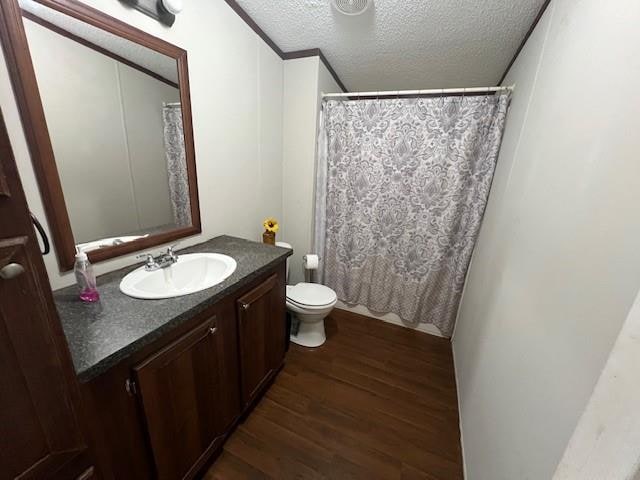 bathroom with vanity, toilet, wood-type flooring, and a textured ceiling