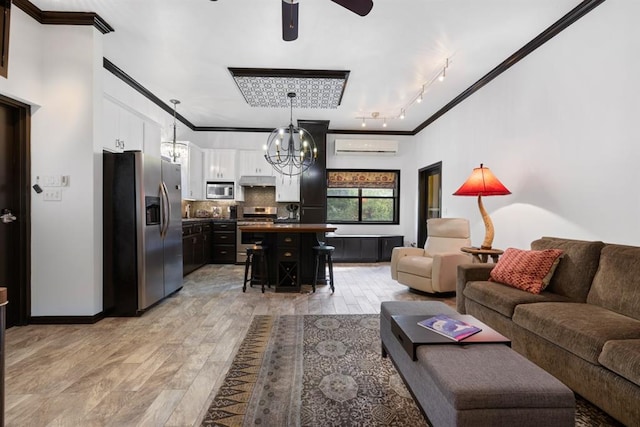 living room featuring a wall unit AC, crown molding, ceiling fan with notable chandelier, and light wood-type flooring