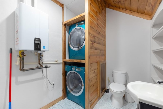 bathroom with sink, tankless water heater, stacked washer / dryer, wooden ceiling, and toilet