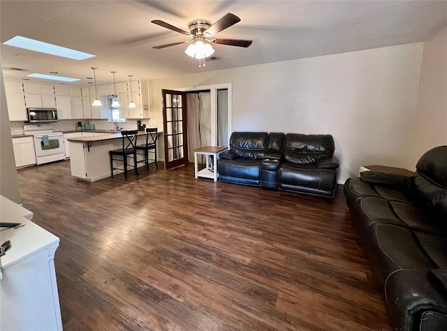 living room with french doors, sink, a skylight, ceiling fan, and dark hardwood / wood-style flooring