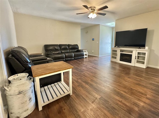 living room featuring ceiling fan, dark hardwood / wood-style flooring, and a fireplace