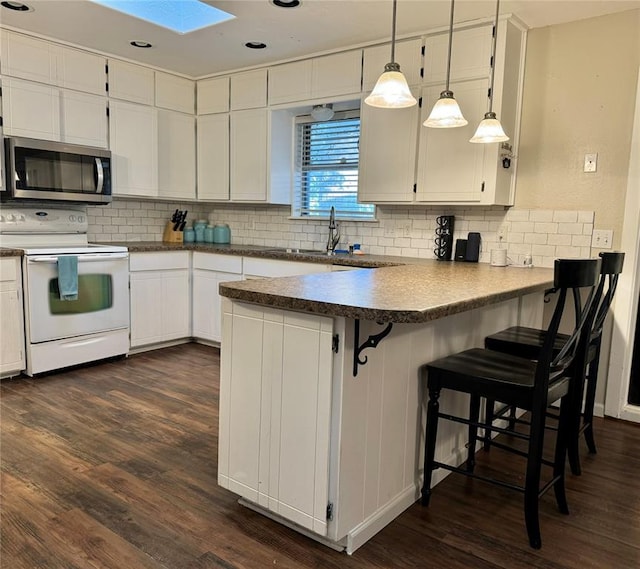 kitchen with a skylight, electric range, dark wood-type flooring, hanging light fixtures, and white cabinets