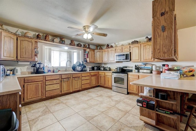 kitchen featuring a textured ceiling, stainless steel appliances, ceiling fan, sink, and light tile patterned floors