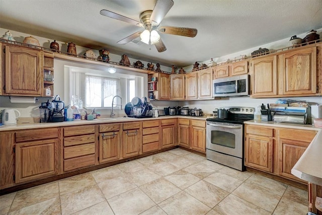 kitchen featuring a textured ceiling, ceiling fan, sink, and appliances with stainless steel finishes