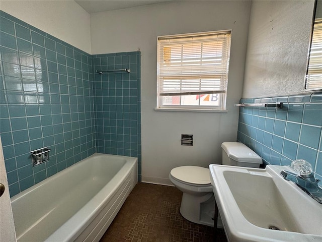 full bathroom with tiled shower / bath combo, toilet, sink, and tile walls