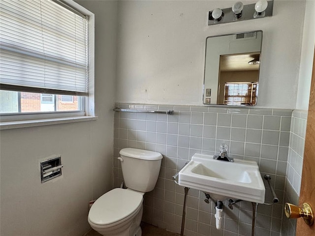 bathroom featuring sink, toilet, and tile walls