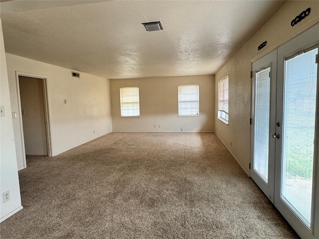 carpeted spare room with french doors and a textured ceiling