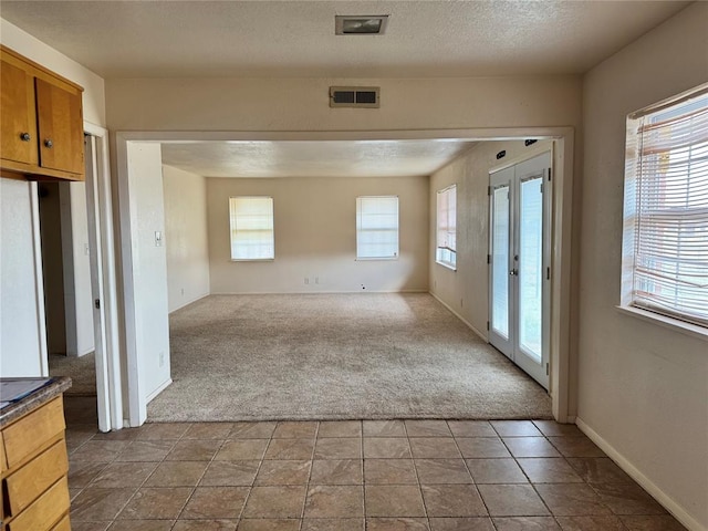 interior space with french doors, a healthy amount of sunlight, and a textured ceiling