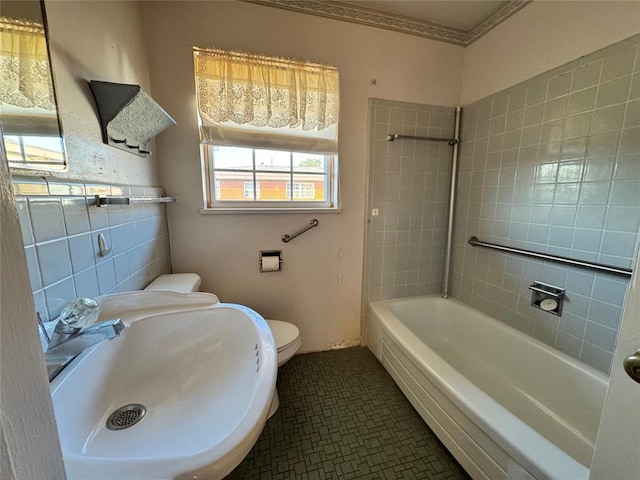 full bathroom featuring tile patterned floors, sink, tiled shower / bath combo, toilet, and tile walls