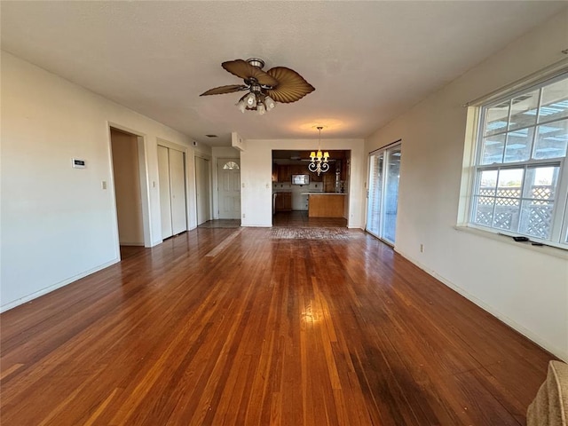 unfurnished living room featuring dark wood-type flooring and ceiling fan with notable chandelier