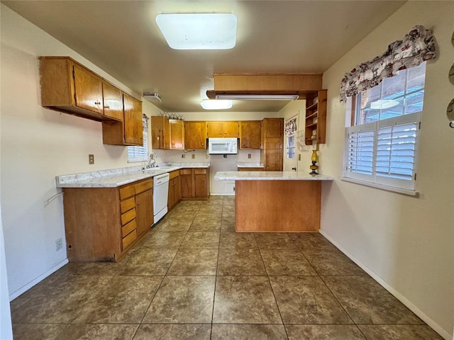 kitchen featuring kitchen peninsula, white appliances, dark tile patterned floors, and sink