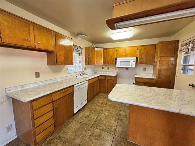 kitchen with white appliances, dark tile patterned flooring, and sink