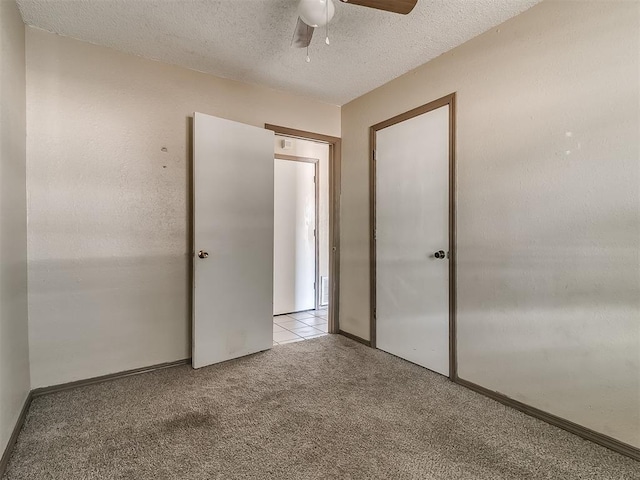 unfurnished bedroom with a textured ceiling, ceiling fan, and light carpet