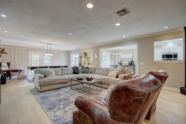 living room featuring light hardwood / wood-style flooring, a textured ceiling, and ornamental molding