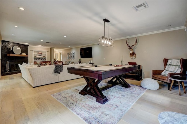 game room featuring light hardwood / wood-style floors, ornamental molding, billiards, and a brick fireplace