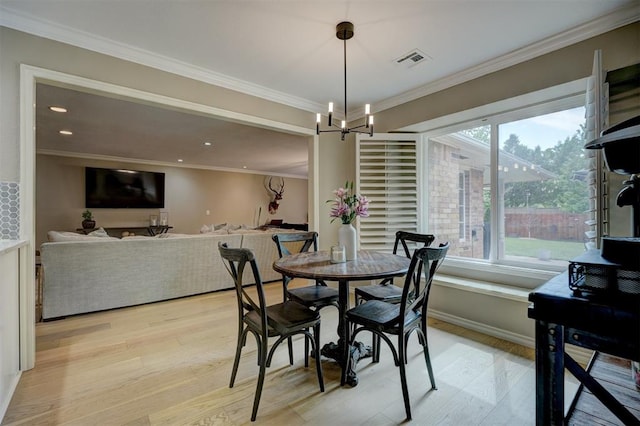 dining space with an inviting chandelier, ornamental molding, and light wood-type flooring