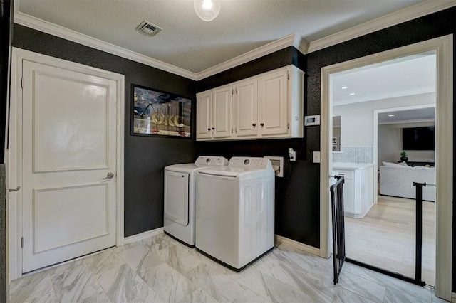 washroom with cabinets, a textured ceiling, washer and clothes dryer, and crown molding