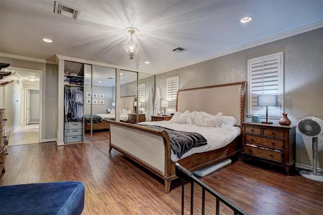 bedroom with hardwood / wood-style floors, a notable chandelier, ornamental molding, and a closet