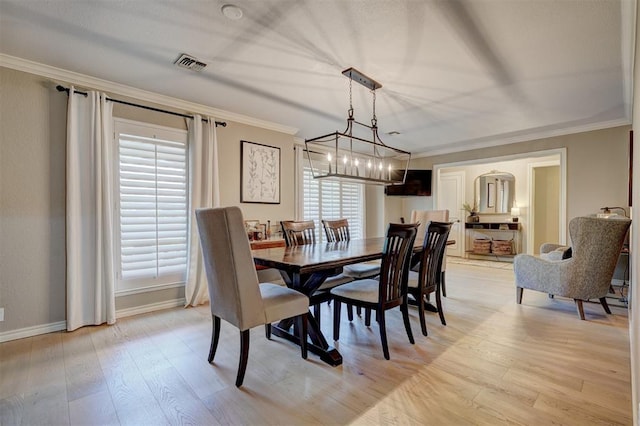 dining space with light hardwood / wood-style flooring, crown molding, and a notable chandelier