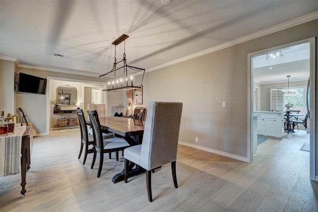 dining space with a notable chandelier, light wood-type flooring, and crown molding