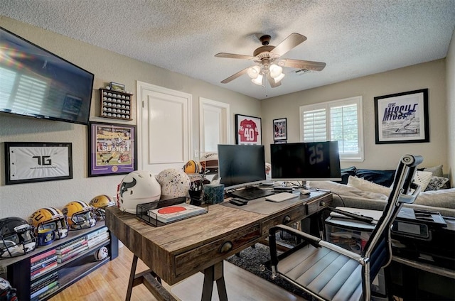 home office with ceiling fan, light hardwood / wood-style floors, and a textured ceiling