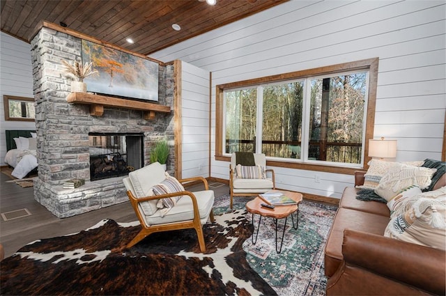 living room with lofted ceiling, wooden ceiling, wooden walls, hardwood / wood-style flooring, and a fireplace