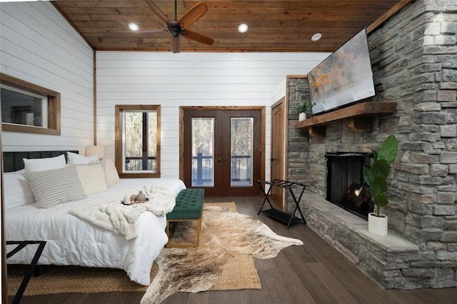 bedroom with wooden ceiling, dark wood-type flooring, french doors, ceiling fan, and a fireplace