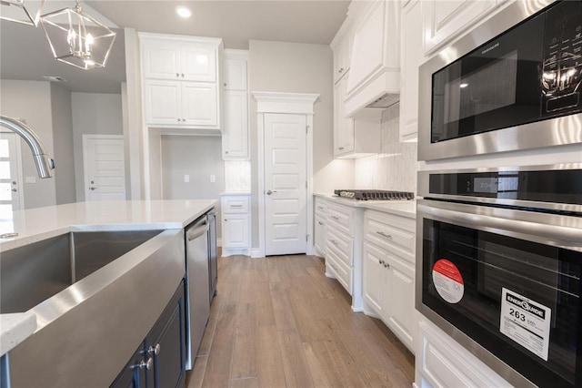 16025 Coneflower Dr, Edmond, OK 73013 - kitchen featuring stainless steel appliances, white cabinetry, light wood-style floors, a chandelier, and recessed lighting