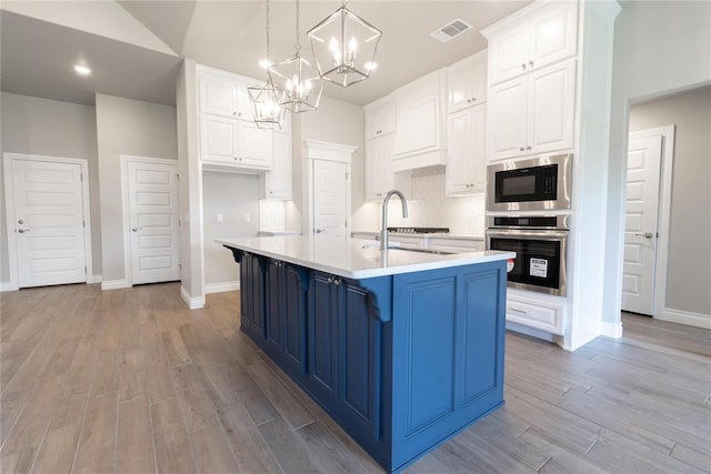 16025 Coneflower Dr, Edmond, OK 73013 - kitchen with stainless steel oven, built in microwave, blue cabinetry, light wood-style flooring, and light countertops