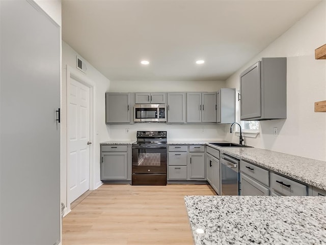 kitchen featuring gray cabinetry, sink, appliances with stainless steel finishes, and light hardwood / wood-style flooring