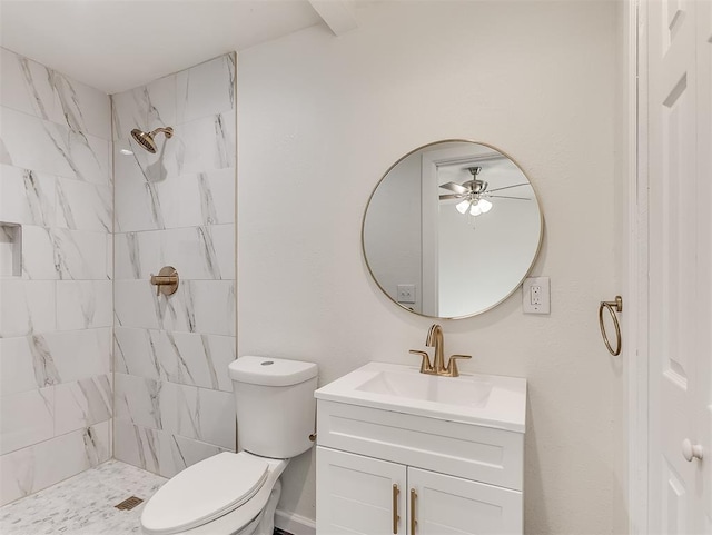 bathroom featuring tiled shower, vanity, toilet, and ceiling fan