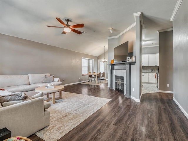 living room featuring lofted ceiling, dark hardwood / wood-style flooring, ceiling fan with notable chandelier, and ornamental molding