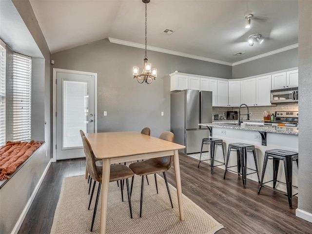 dining area featuring vaulted ceiling, an inviting chandelier, dark hardwood / wood-style flooring, and crown molding