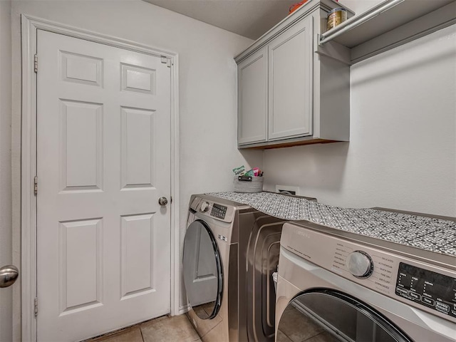 laundry area featuring light tile patterned floors, cabinets, and washer and dryer