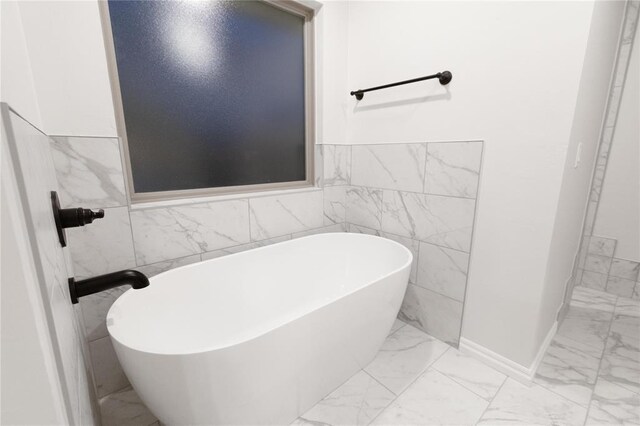 9201 Lupine Rd, Yukon, OK 73099 - bathroom featuring marble finish flooring, tile walls, a soaking tub, and wainscoting