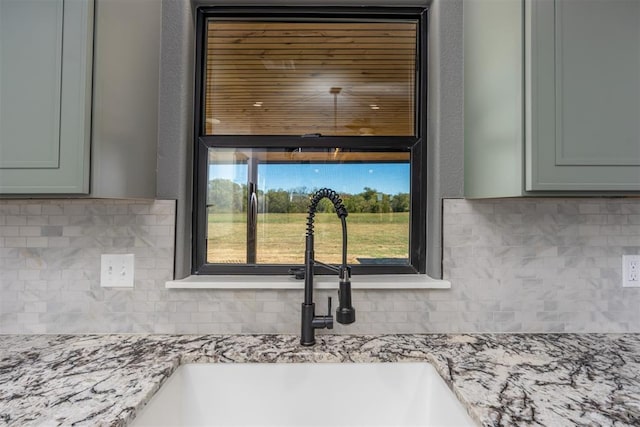 interior details featuring decorative backsplash, light stone counters, and sink