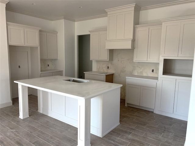 kitchen with crown molding, sink, a kitchen island, and white cabinets