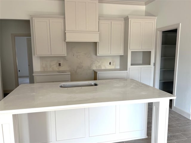 kitchen featuring white cabinetry and an island with sink