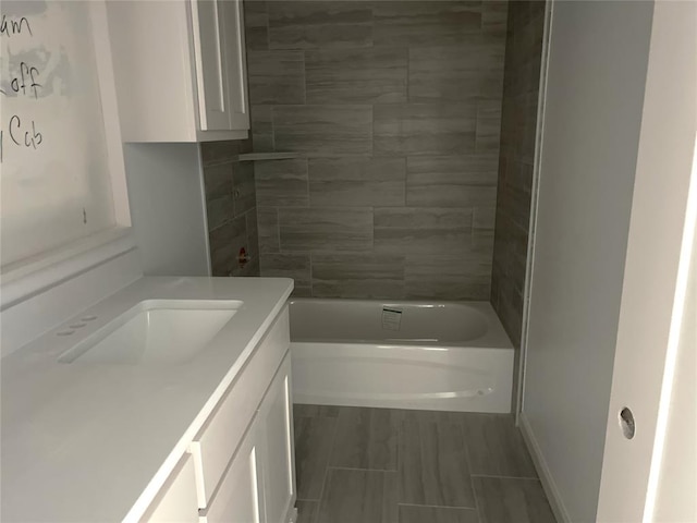 bathroom featuring tiled shower / bath combo and vanity