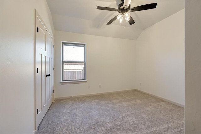 unfurnished bedroom featuring lofted ceiling, baseboards, a ceiling fan, and light colored carpet