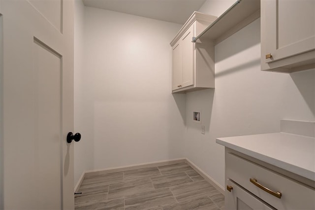 clothes washing area with washer hookup, cabinet space, and baseboards