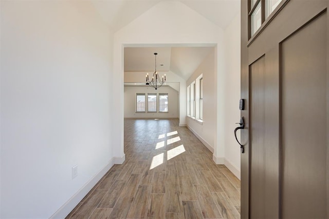 entrance foyer featuring vaulted ceiling, baseboards, light wood-style flooring, and an inviting chandelier