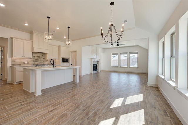 kitchen with tasteful backsplash, stainless steel microwave, open floor plan, light countertops, and a notable chandelier