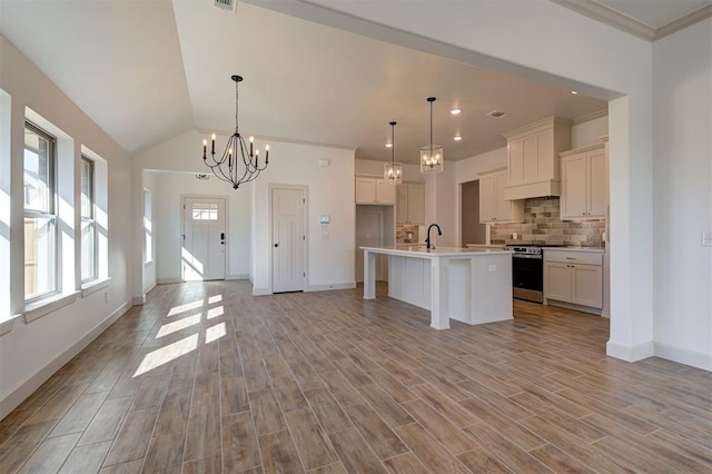 kitchen featuring light wood finished floors, tasteful backsplash, open floor plan, light countertops, and gas stove