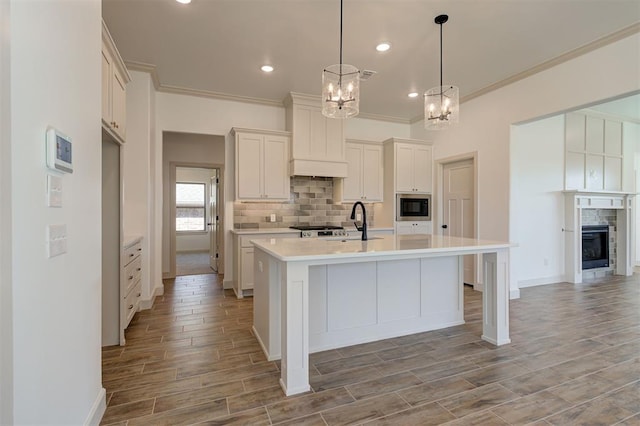 kitchen featuring light countertops, stainless steel microwave, light wood-style flooring, backsplash, and a sink