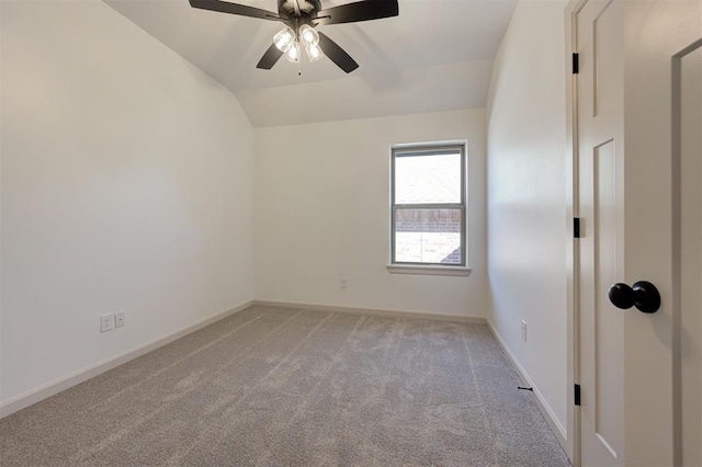 spare room featuring lofted ceiling, a ceiling fan, light colored carpet, and baseboards