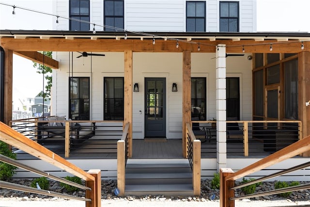 view of exterior entry with ceiling fan and a porch