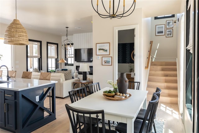 dining space featuring light wood-type flooring, an inviting chandelier, and sink